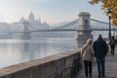 Älteres Paar spaziert am Donauufer in Budapest mit Blick auf die Kettenbrücke und das Parlament im Morgendunst